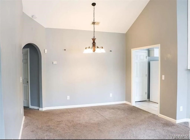 carpeted spare room with an inviting chandelier and high vaulted ceiling