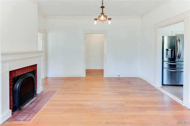 unfurnished living room with a tiled fireplace, light hardwood / wood-style flooring, ornamental molding, and a notable chandelier