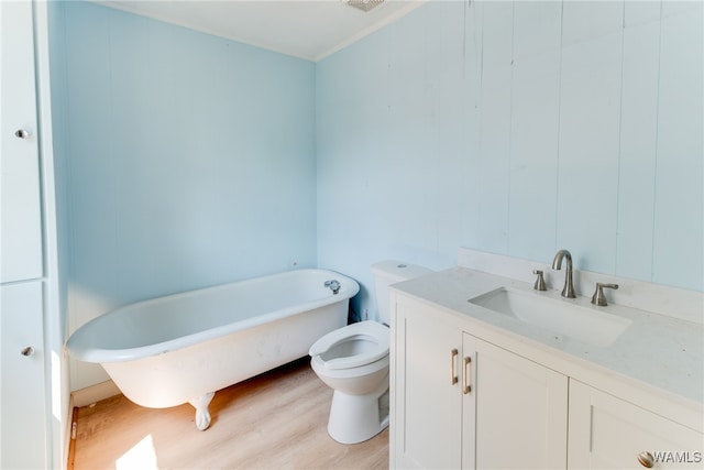 bathroom featuring hardwood / wood-style flooring, vanity, toilet, and a tub to relax in