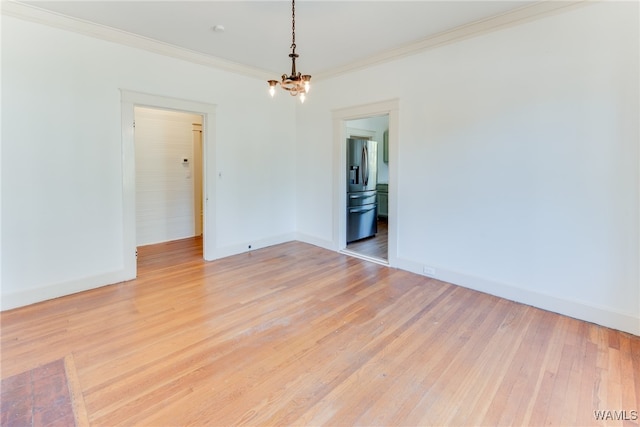 spare room with a notable chandelier, light wood-type flooring, and ornamental molding