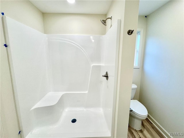 full bathroom with baseboards, toilet, walk in shower, and wood finished floors