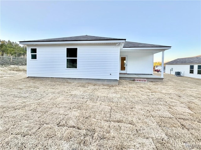 back of house featuring central air condition unit, a lawn, a patio, and roof with shingles