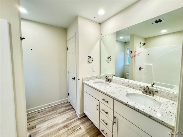 bathroom with a shower, toilet, wood finished floors, and a sink