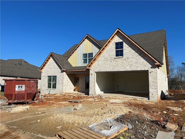 view of front facade featuring board and batten siding, a garage, brick siding, and a shingled roof