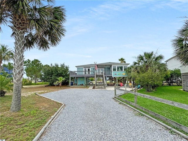 beach home with a carport, stairway, gravel driveway, and a front yard