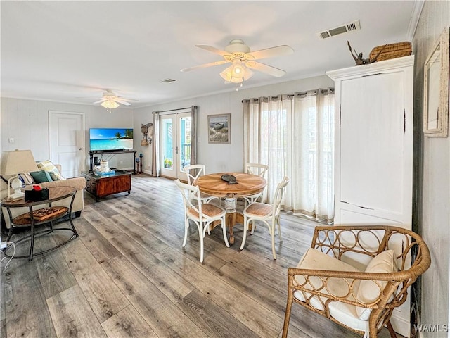 dining space with light wood-type flooring, visible vents, a ceiling fan, french doors, and crown molding