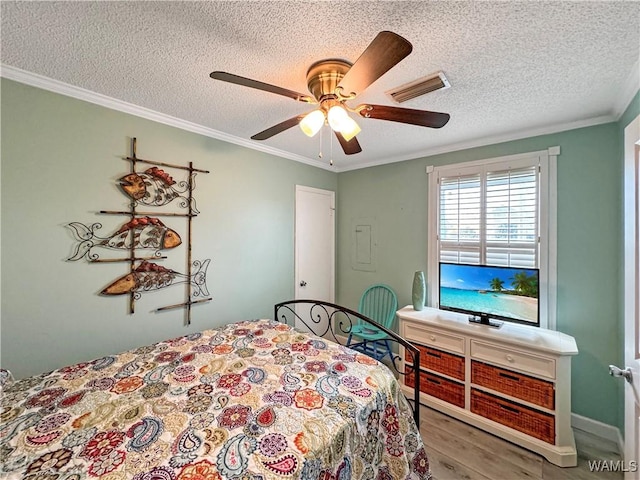 bedroom featuring visible vents, wood finished floors, a textured ceiling, and ornamental molding