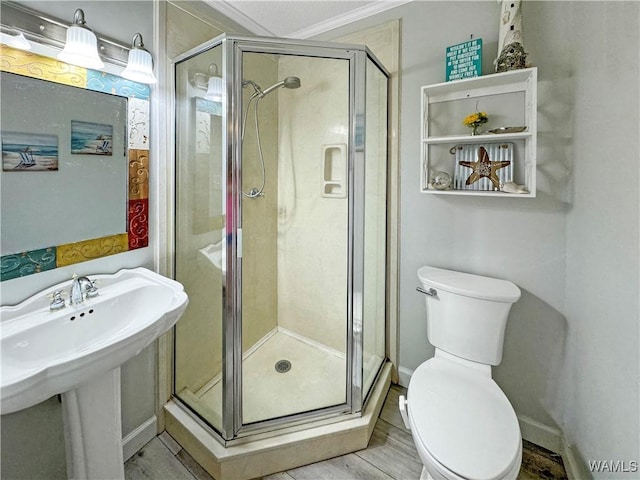 bathroom featuring toilet, a sink, wood finished floors, a shower stall, and baseboards