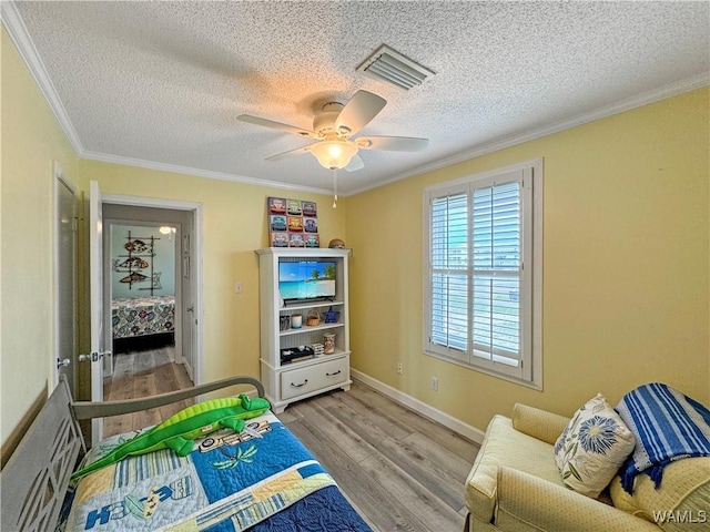 bedroom with visible vents, ornamental molding, a ceiling fan, wood finished floors, and baseboards