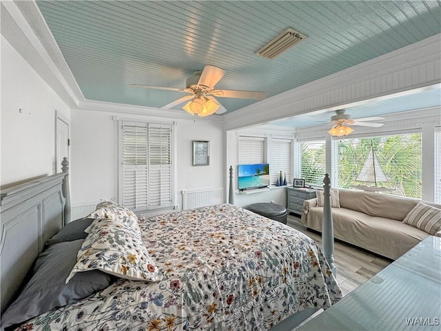 bedroom with visible vents, wood finished floors, a ceiling fan, and crown molding