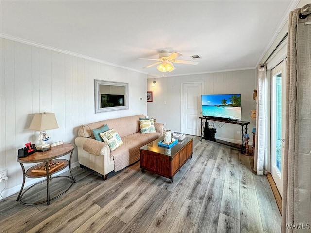 living room featuring visible vents, a ceiling fan, crown molding, and light wood finished floors