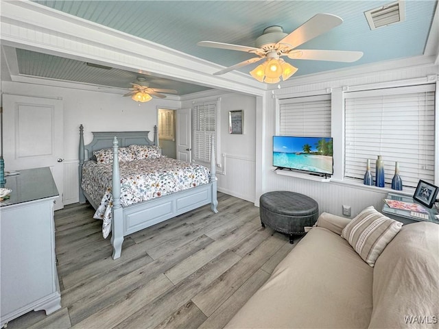 bedroom with crown molding, light wood-style flooring, visible vents, and ceiling fan