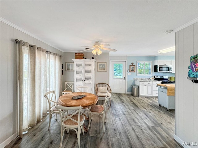 dining area with ceiling fan, baseboards, wood finished floors, and ornamental molding