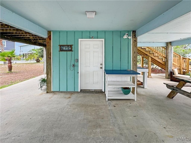 view of exterior entry with board and batten siding and a patio area