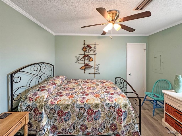 bedroom featuring visible vents, crown molding, wood finished floors, a textured ceiling, and a ceiling fan