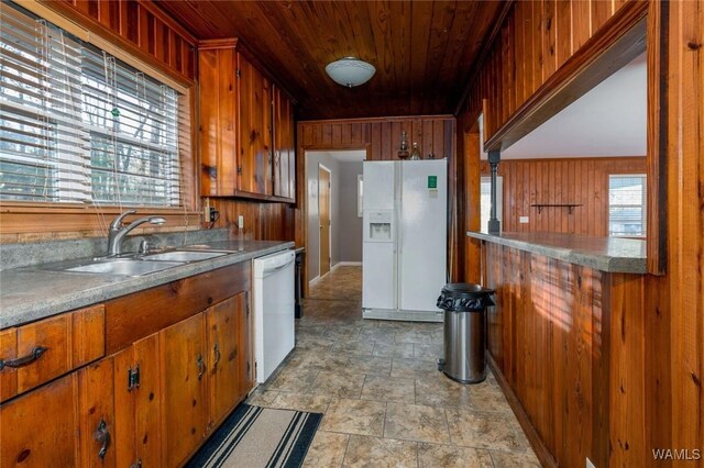 kitchen featuring a sink, white appliances, wood ceiling, and wood walls