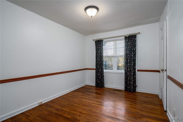 spare room with visible vents, baseboards, and wood finished floors