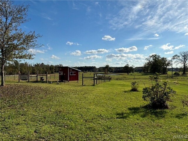 view of yard with a rural view, fence, and an outdoor structure