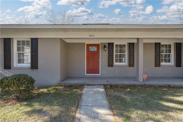 entrance to property with a lawn and a porch