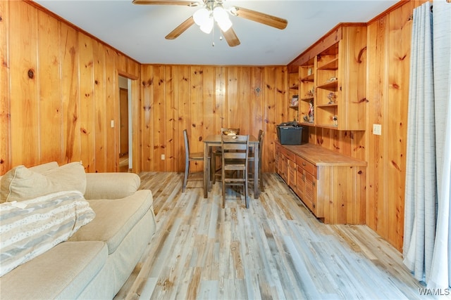 office space featuring wooden walls, crown molding, ceiling fan, and light hardwood / wood-style floors