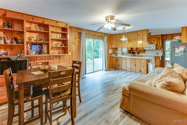 interior space with ceiling fan, wood walls, and light wood-type flooring