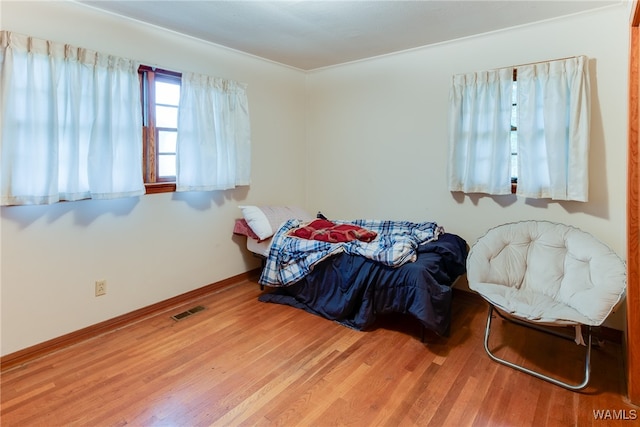 bedroom with wood-type flooring and ornamental molding