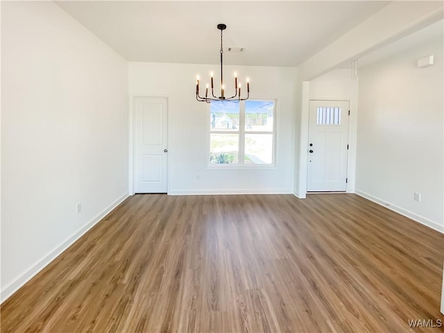 unfurnished dining area with a notable chandelier and dark hardwood / wood-style flooring