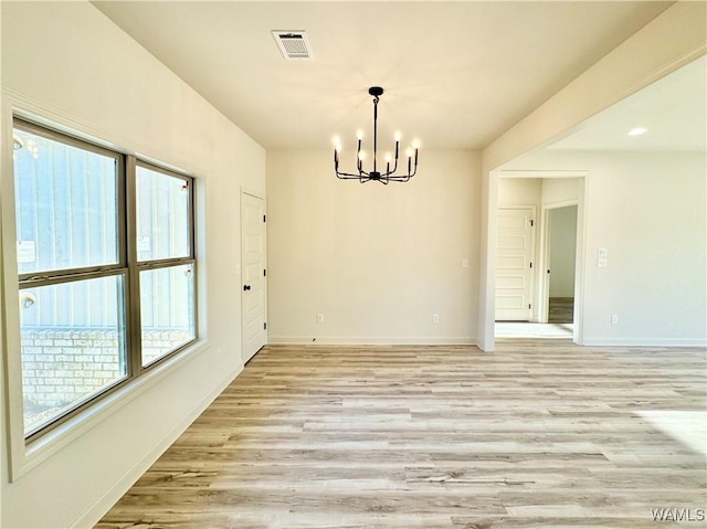 unfurnished dining area with light wood finished floors, visible vents, a chandelier, and baseboards