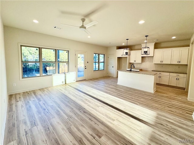 kitchen featuring light wood-type flooring, visible vents, tasteful backsplash, and open floor plan