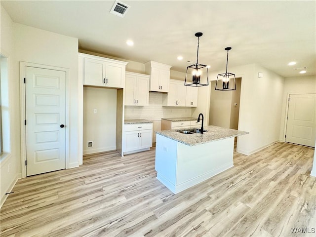 kitchen featuring white cabinetry, light wood-style flooring, visible vents, and a sink