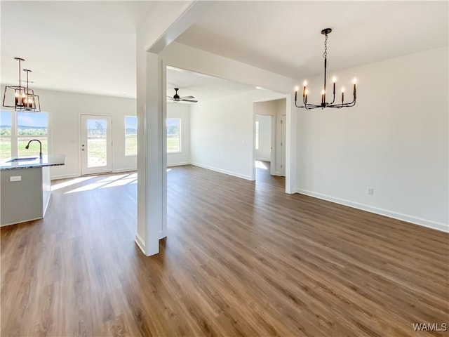 interior space with dark hardwood / wood-style flooring, ceiling fan with notable chandelier, and sink