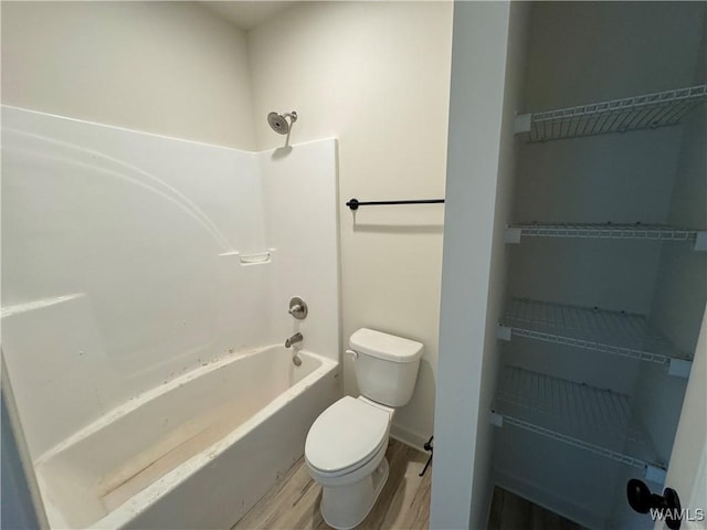 bathroom with toilet, shower / washtub combination, and wood finished floors