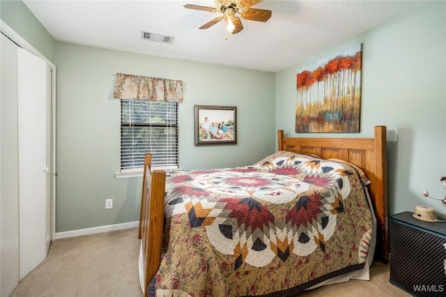 bedroom featuring ceiling fan, light colored carpet, and a textured ceiling