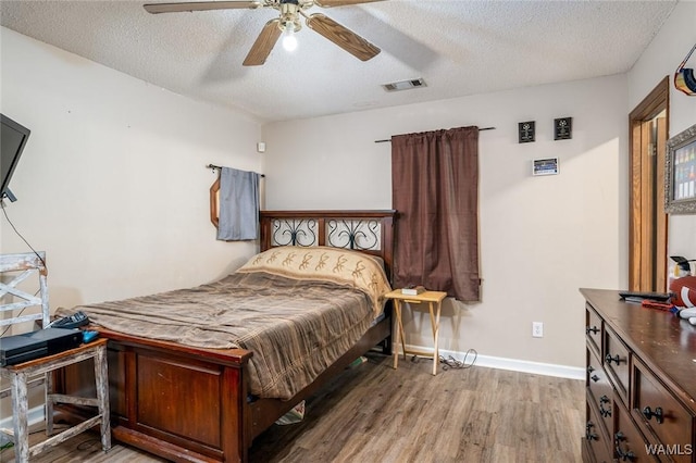 bedroom with ceiling fan, light hardwood / wood-style flooring, and a textured ceiling