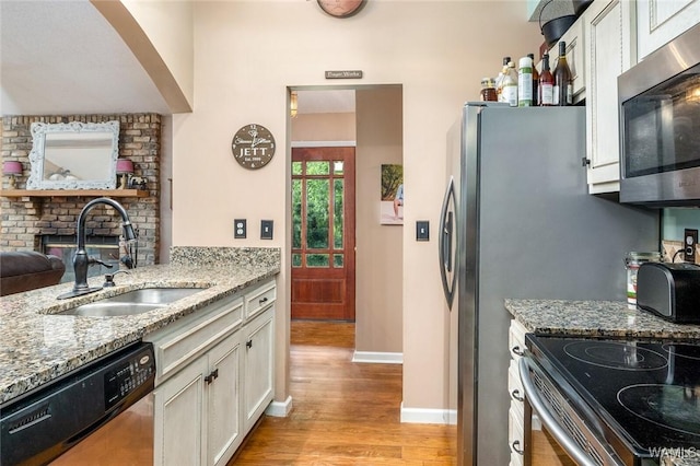 kitchen featuring white cabinetry, sink, light stone counters, stainless steel appliances, and light hardwood / wood-style flooring