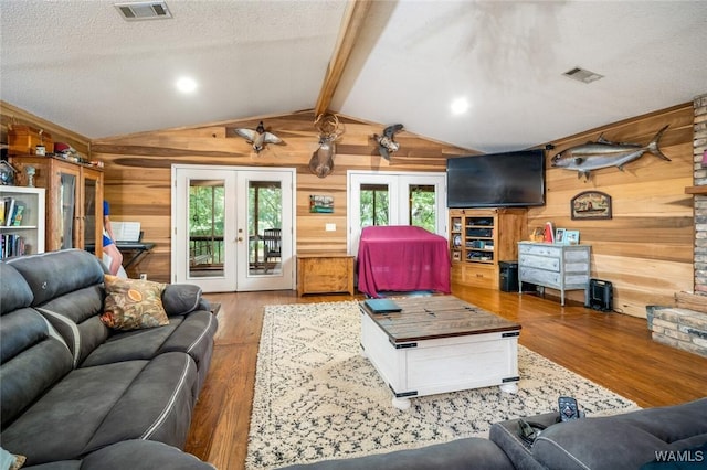 living room featuring vaulted ceiling with beams, wooden walls, french doors, and wood-type flooring