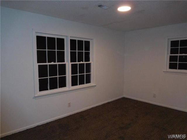 unfurnished room featuring dark carpet