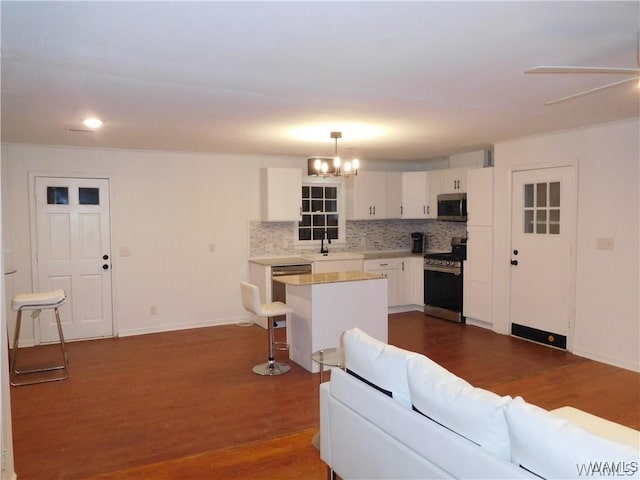 living room with dark hardwood / wood-style floors, sink, and ceiling fan with notable chandelier