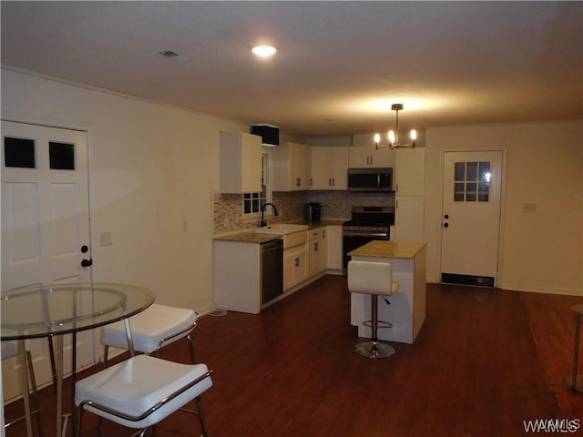 kitchen featuring black appliances, white cabinets, dark hardwood / wood-style floors, a kitchen island, and hanging light fixtures