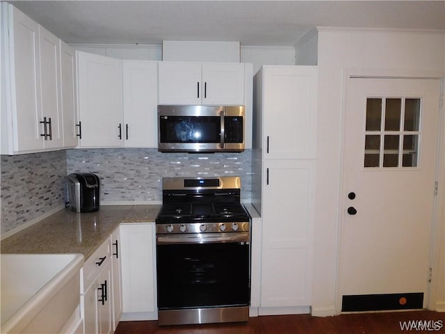 kitchen featuring white cabinetry, light stone countertops, tasteful backsplash, appliances with stainless steel finishes, and ornamental molding