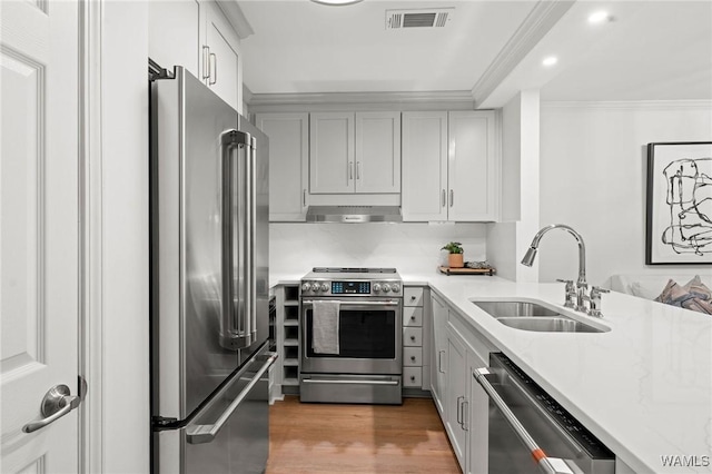 1228 8th St Unit 412, Tuscaloosa, AL 35401 - kitchen featuring stainless steel appliances, light countertops, under cabinet range hood, ornamental molding, and wood finished floors