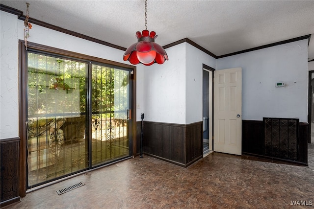 empty room with wood walls, crown molding, and a textured ceiling