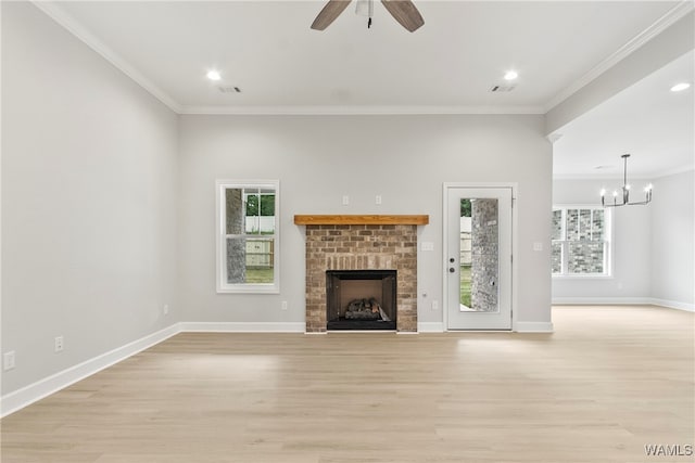 unfurnished living room featuring a brick fireplace, ornamental molding, ceiling fan with notable chandelier, and light wood-type flooring