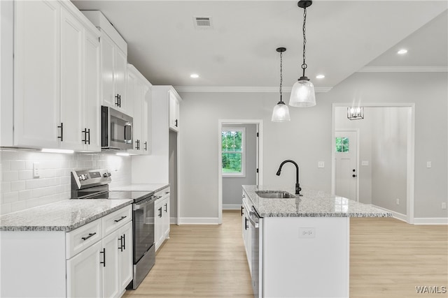 kitchen with white cabinetry, sink, stainless steel appliances, decorative light fixtures, and a kitchen island with sink