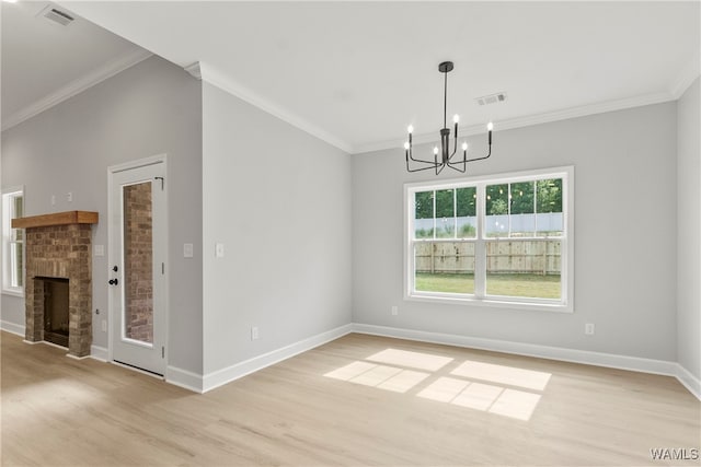 unfurnished dining area with a chandelier, light wood-type flooring, a brick fireplace, and crown molding