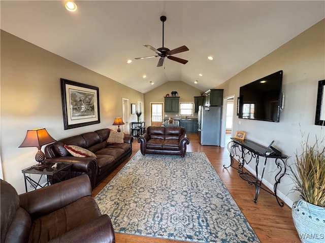 living room with hardwood / wood-style flooring, ceiling fan, and vaulted ceiling