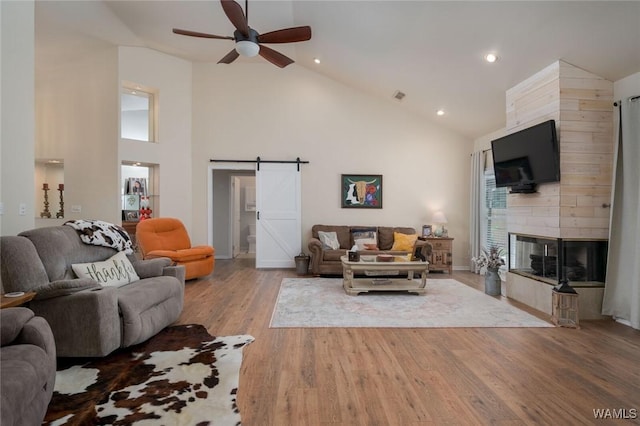 1606 Mallard Cir, Tuscaloosa, AL 35405 - living area with a barn door, ceiling fan, high vaulted ceiling, a tiled fireplace, and wood finished floors