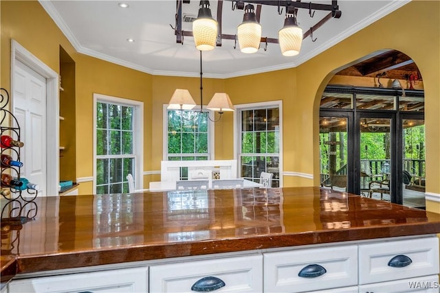 kitchen with decorative light fixtures, crown molding, arched walkways, recessed lighting, and white cabinetry