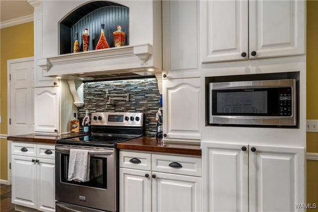kitchen with crown molding, wooden counters, white cabinetry, appliances with stainless steel finishes, and backsplash