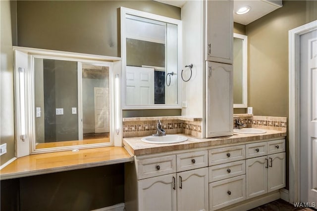 full bath featuring a sink, tasteful backsplash, and double vanity
